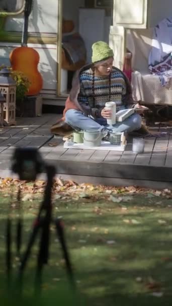 一个漂亮的嬉皮士女孩带着一本书和一杯热饮料在秋天的花园 高质量的4K镜头 — 图库视频影像