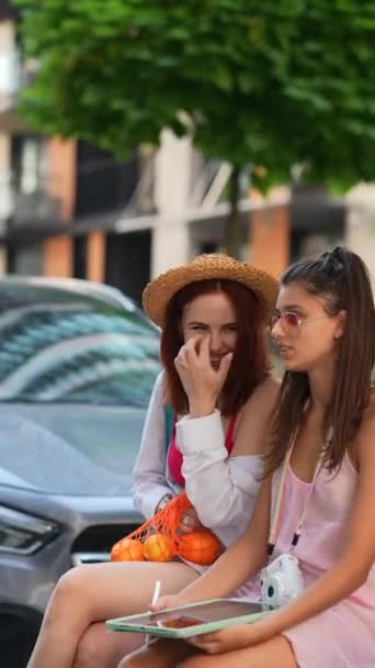 两个精力充沛的年轻姑娘坐在那里 手里拿着一块石碑和水果 享受着城市的氛围 高质量的4K镜头 — 图库视频影像