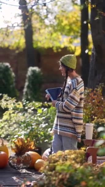 秋の日差しの中で ヒップスターの少女は屋外で天気を楽しんでいる間にタブレットで彼女の仕事を披露します 高品質の4K映像 — ストック動画