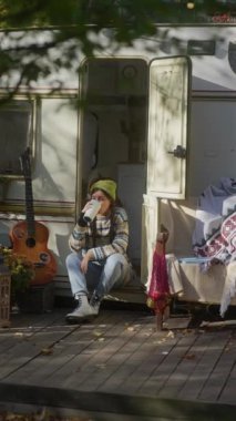 Hippi yaşam tarzını tamamen benimseyen şık genç bir bayan, bahçede bir kitap ve sıcak bir içecekten hoşlanıyor. Yüksek kalite 4k görüntü