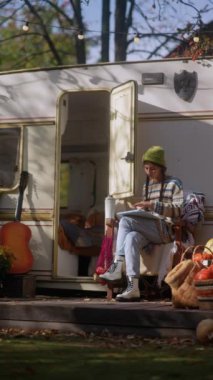 Hipster bir havası olan şık ve hoş genç bir bayan, bahçede sıcak bir içecekle birlikte tabletini kullanırken görülüyor. Yüksek kalite 4k görüntü