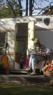 Bir hipster meraklısı sonbahar bahçesinde iş ve rahatlamayı birleştirir, tabletini kullanır ve sıcak bir içecek yudumlar. Yüksek kalite 4k görüntü