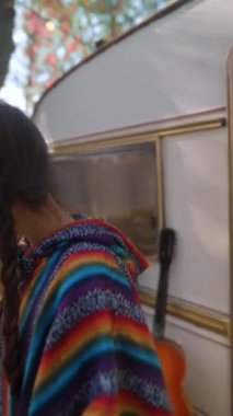 Elinde bir fincan sıcak içecekle hippi kıyafetli genç ve güzel bir kadın karavandaki hayattan bahsediyor. Yüksek kalite 4k görüntü