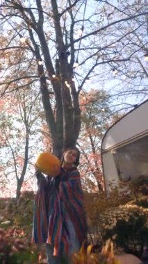 Hippi kıyafetiyle, güneşli bir sonbahar gününde güzel ve genç bir kadın balkabağıyla görülüyor. Yüksek kalite 4k görüntü