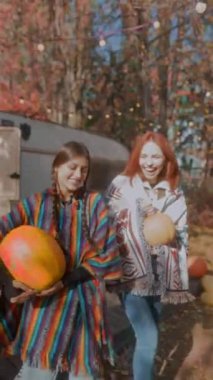 İki genç hippi kız ellerinde balkabaklarıyla sonbahar havasını kucaklarken görülüyor. Yüksek kalite 4k görüntü