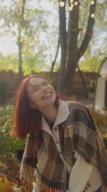 Hippi tarzı giyinmiş güzel bir kızıl kız bahçedeki güneşli sonbahar havasının tadını çıkarıyor. Yüksek kalite 4k görüntü