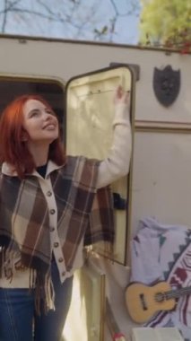 Sonbahar güneşini kucaklayan, hippi kostümlü çarpıcı kızıl saçlı kız bahçedeki hoş havanın tadını çıkarıyor. Yüksek kalite 4k görüntü