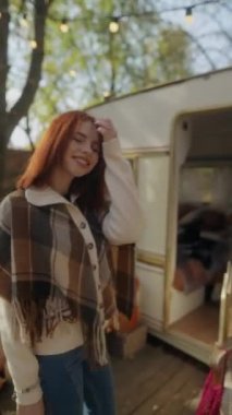 Hippi kıyafetiyle, kızıl saçlı ışıl ışıl genç bir bayan bahçedeki güneşli sonbahar gününün tadını çıkarıyor. Yüksek kalite 4k görüntü