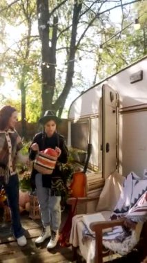 Hippi gibi giyinmiş iki güzel kız sonbahar bahçesinde ellerinde balkabağı tutuyor. Yüksek kalite 4k görüntü