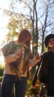 Hippi kıyafetli iki genç dansçı sonbahar bahçesinde dans ediyorlar. Yüksek kalite 4k görüntü