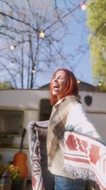 Hippi cazibesiyle, kızıl saçlı güzel genç bir kadın güneşli bir sonbahar gününde bahçede güneşleniyor. Yüksek kalite 4k görüntü