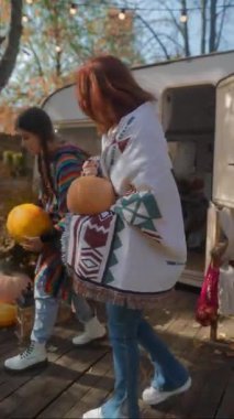 Sonbahar bahçesinde ellerinde balkabaklarıyla hippi kıyafeti giymiş iki güzel kız. Yüksek kalite 4k görüntü