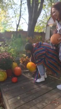 Sonbahar ruhunun tadını çıkaran, hippi kıyafetli iki muhteşem kız bahçede balkabağı tutuyor. Yüksek kalite 4k görüntü