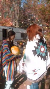 Sonbahar bahçesi, her biri balkabağı olan hippi kıyafetli iki zarif genç bayanın arka planı. Yüksek kalite 4k görüntü