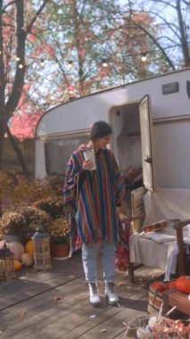 Genç bir kadın, hippi ruhunu yayıyor, elinde sıcak içkisiyle karavan hayatı hakkında sohbet ediyor. Yüksek kalite 4k görüntü