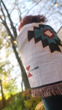 Hippi kıyafetli güzel bir kızıl kız bahçede güneşli sonbahar havasının tadını çıkarıyor. Yüksek kalite 4k görüntü