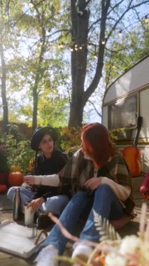 Sonbahar manzarasını kucaklayan bu çekici genç hippi kızlar sıcak içeceklerinden zevk alıyorlar. Yüksek kalite 4k görüntü