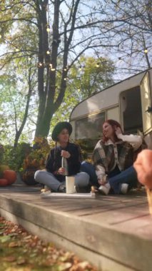 Güneşli terasta, hippi kıyafetli güzel kızlar keyifli bir sonbahar gününde çaylarını yudumluyorlar. Yüksek kalite 4k görüntü