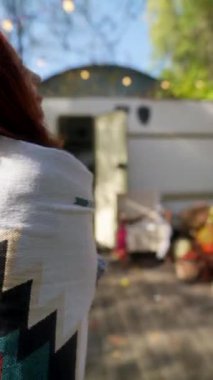 Hippi kıyafetiyle, kızıl saçlı ışıl ışıl genç bir bayan bahçedeki güneşli sonbahar gününün tadını çıkarıyor. Yüksek kalite 4k görüntü