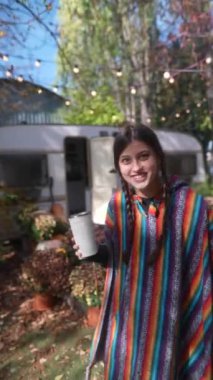 Hippi havasıyla, çarpıcı genç bir bayan elinde bir fincan sıcak içecek tutuyor ve sıcak bir günde karavanda hayatı tartışıyor. Yüksek kalite 4k görüntü