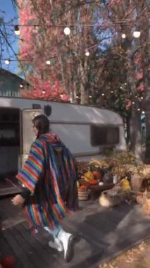 Hippi gibi giyinmiş, hoş ve genç bir kadın elinde bir fincan sıcak içecekle karavan hayatı hakkında görüşlerini paylaşırken görülüyor. Yüksek kalite 4k görüntü