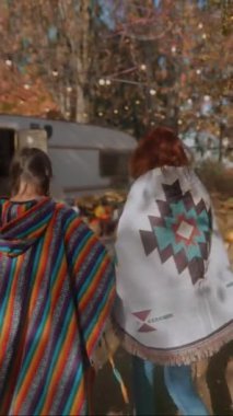 Hippi gibi giyinmiş iki güzel kız sonbahar bahçesinde ellerinde balkabağı tutuyor. Yüksek kalite 4k görüntü