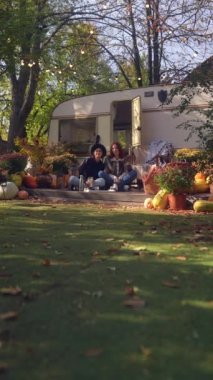 Göz alıcı hippi kızlar çay yudumlar ve karavanın yanındaki güzel bir sonbahar bahçesinde sohbet ederler. Yüksek kalite 4k görüntü