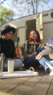 Hippi kızlar güneşli bir sonbahar gününde terasta sıcak çay yudumluyorlar. Yüksek kalite 4k görüntü
