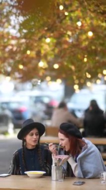 Şık şehirleriyle, çarpıcı genç bayanlar sonbahar terasında çay yudumluyorlar. Yüksek kalite 4k görüntü