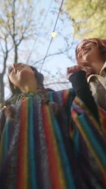 Sonbahar atmosferinin tadını çıkaran hippiler gibi giyinmiş iki genç kız dans ediyor. Yüksek kalite 4k görüntü