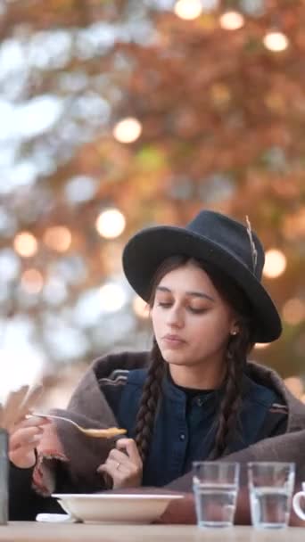 一位年轻貌美的女士 穿上秋天的衣服 在户外露台上享用着她的饭菜 高质量的4K镜头 — 图库视频影像