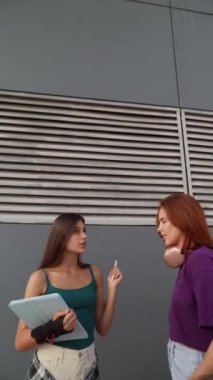 İki genç dişi aktif olarak şehir ortamında önemli bir konu hakkında sohbet ediyorlar. Yüksek kalite 4k görüntü