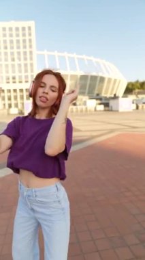 Şehir sakinleri, kulaklıklı güzel bir kızıl saçlının dansına tanıklık ediyor. Yüksek kalite 4k görüntü