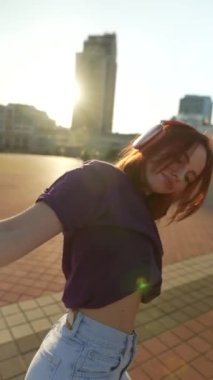 Güneşli bir gün, kulaklıklı, çarpıcı kızıl saçlı bir bayanın dansına zemin hazırlıyor. Yüksek kalite 4k görüntü