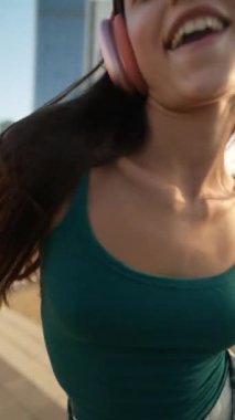 Güneşli bir günde, genç ve güzel bir kadın kulaklıkla dans eder. Yüksek kalite 4k görüntü