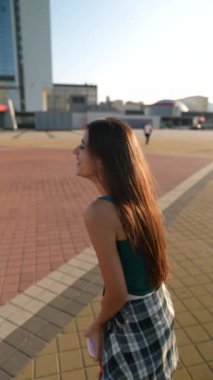 Şehir meydanında enerjik bir şekilde dans eden dinamik genç bir kadın kulaklık takıyor. Yüksek kalite 4k görüntü