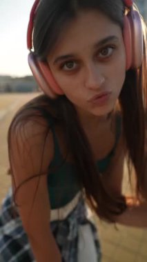 Canlı genç bir bayan şehir meydanında kulaklık takarak dans ediyor. Yüksek kalite 4k görüntü