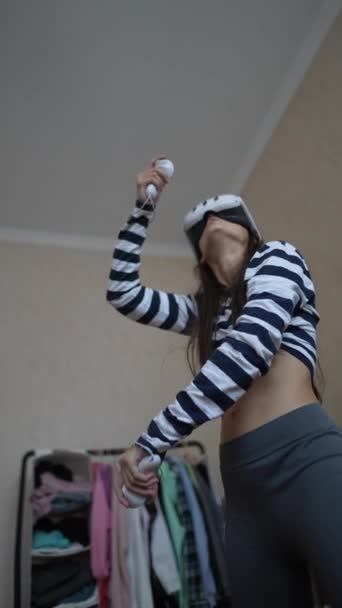 一个年轻的女运动员用一个虚拟现实耳机在她家的范围内玩电子游戏 高质量的4K镜头 — 图库视频影像