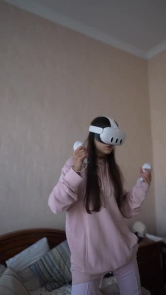 一个穿着粉色睡衣的年轻漂亮的女人用一个虚拟现实耳机玩电子游戏 高质量的4K镜头 — 图库视频影像