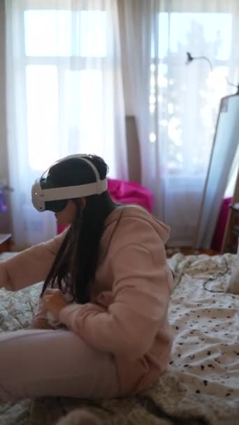 一位迷人的女士穿着粉色睡衣 带着一个虚拟现实耳机玩电子游戏 高质量的4K镜头 — 图库视频影像