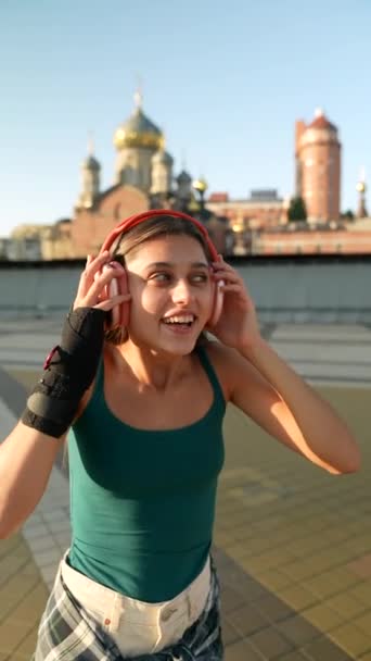Στην Πλατεία Της Πόλης Μια Ζωντανή Νεαρή Γυναίκα Χορεύει Ακουστικά — Αρχείο Βίντεο