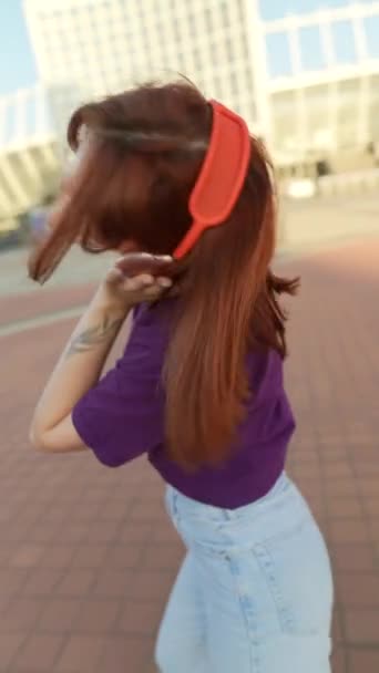 街の広場の中心部でヘッドフォンダンスを着用した豪華な赤毛 高品質の4K映像 — ストック動画