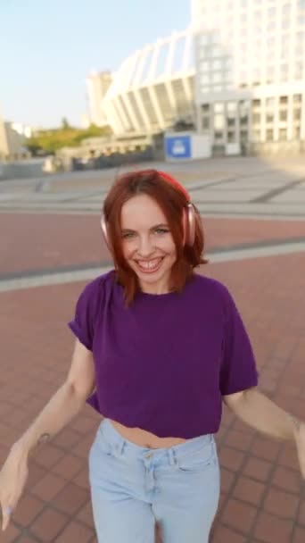 Słuchawkami Zdobiącymi Jej Uszy Czarująca Ruda Tańczy Centralnym Placu Miasta — Wideo stockowe