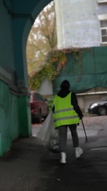 Özel üniformalı genç bir kadın bir sonbahar şehrinin sokaklarını temizliyor. Yüksek kalite 4k görüntü