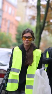 Aktif genç bayan gönüllü sokakta özel bir üniformayla çöp topluyor. Yüksek kalite 4k görüntü