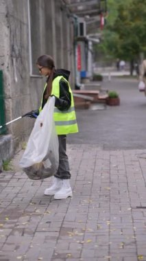 Bir kız gönüllü çöpçülerin yardımıyla şehrin sokaklarını temizlemeye yardım ediyor. Yüksek kalite 4k görüntü