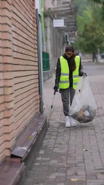 ゴミの舌を手にした若い女性ボランティアが路上でゴミを拾う 高品質の4K映像 — ストック動画