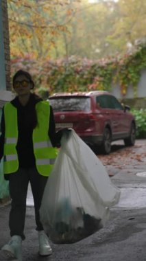 Genç bir bayan gönüllü, şehrin sokaklarını temiz tutmak için çöp toplayıcıları kullanıyor. Yüksek kalite 4k görüntü