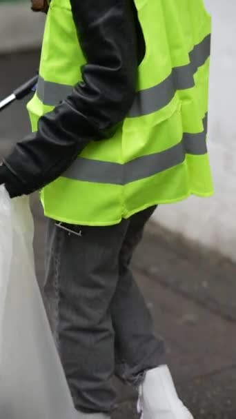 一位穿着特定服装的年轻女士在清理秋天的街道时捡垃圾 高质量的4K镜头 — 图库视频影像