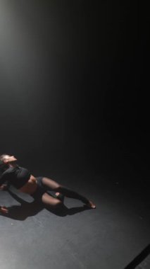 Çağdaş bir dansla meşgul olan genç bir kadın loş bir stüdyoda zarif bir şekilde hareket ediyor. Yüksek kalite 4k görüntü